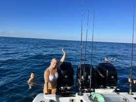 Two friends enjoy a refreshing swim in the ocean while a fishing boat is anchored nearby, capturing the essence of a fun day on the water.