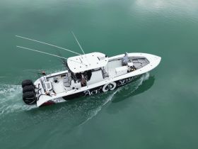 A fishing boat named 'Ace Spade' is underway in clear turquoise waters, showcasing an exciting day on the water for fishing enthusiasts.