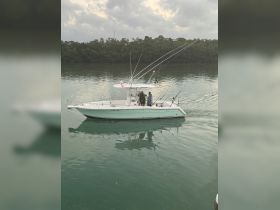A fishing boat with people on board navigates through calm waters, showcasing the perfect setting for a day of fishing adventures.