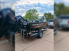 A sleek Tracker boat parked on a trailer, showcasing its modern design and powerful Mercury engine, perfect for fishing or recreational outings.