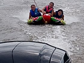 Three friends enjoy an exhilarating tubing ride on the water, showcasing the thrill of summer water activities and group fun.