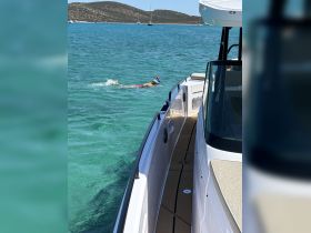 A child enjoys snorkeling in crystal-clear waters, with a boat nearby, showcasing the perfect day for aquatic adventures.