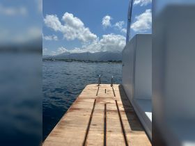A serene view of a boat's rear deck with a clear blue sky and distant mountains, perfect for enjoying the tranquility of the open water.