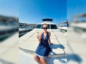 A woman enjoys a refreshing cocktail while relaxing on the deck of a boat under the bright sun, perfect for summer celebrations on the water.