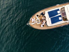 A lively group enjoys a delightful gathering on a yacht, complete with cocktails and snacks, showcasing the perfect setting for celebrations on the water.