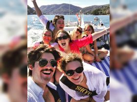 A lively group of friends celebrates aboard a boat, showcasing joy and camaraderie against a stunning water backdrop — perfect for unforgettable summer adventures.
