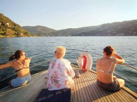 A group of friends enjoys a relaxing moment on the deck of a boat at sunset, surrounded by stunning scenery — perfect for memorable outings on the water.