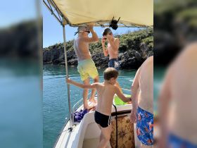 A group of children enjoys a fun day on the boat, preparing for water activities in a scenic coastal setting.