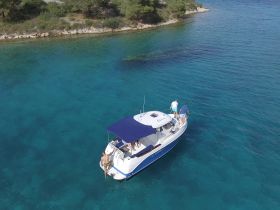 A group of friends enjoys a sunny day on a boat, with one person preparing to jump into the crystal-clear turquoise waters — a perfect scene for summer adventures.