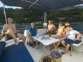 A joyful family enjoys their time on a boat, sharing snacks and laughter against a scenic backdrop — perfect for memorable summer outings.