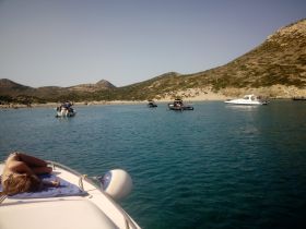 A relaxing day on the water with friends, featuring a group enjoying the beach and swimming while lounging on a boat — perfect for summer adventures.