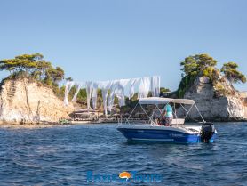 A speedboat named 'Poseidon' is anchored near a scenic coastline, showcasing the beautiful landscape and clear waters — perfect for exploring coastal destinations.