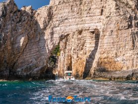 A scenic view of a boat navigating through a stunning rock formation along the coastline, showcasing the beauty of nature and adventure on the water.