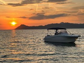 A serene sunset view featuring a boat cruising on calm waters, perfect for evening excursions and scenic adventures.