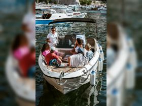 A lively group gathers on a boat, engaging with a guide, perfect for team-building activities or group outings on the water.