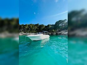 A scenic view of a boat anchored in crystal-clear turquoise waters, with a person swimming nearby, perfect for a relaxing day on the water.