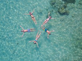 A group of friends floats together in crystal-clear waters, enjoying a perfect day under the sun — an ideal scene for summer adventures and relaxation.
