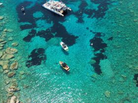 A stunning aerial view of boats in crystal-clear turquoise waters, showcasing a vibrant marine landscape ideal for island hopping adventures.