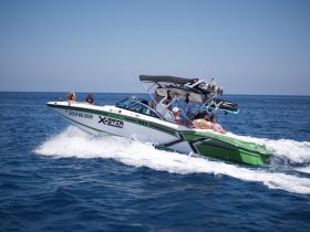 A lively group enjoys a thrilling ride on a wakeboarding boat, showcasing the excitement of on-water activities under the sun.