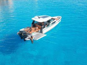 Two individuals enjoy a sunny day on a boat in crystal-clear turquoise waters, perfect for a relaxing getaway or aquatic adventure.