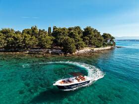 A stunning aerial view of a speedboat navigating through crystal-clear waters, showcasing the beauty of the coastline and lush greenery in the background.