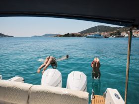 Two individuals dive into the crystal-clear waters from a boat, capturing the essence of summer fun and adventure on the water.