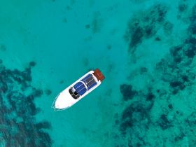 A stunning aerial view of a sleek speedboat gliding over crystal-clear turquoise waters, perfect for exploring beautiful coastal destinations.