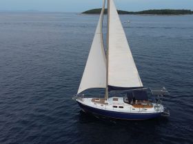 A stunning aerial view of a sailboat gracefully navigating through calm waters, showcasing its elegant sails and sleek design — perfect for sailing enthusiasts.
