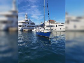 A beautiful blue yacht docked in a marina, surrounded by other vessels under a clear blue sky — perfect for showcasing boating adventures.