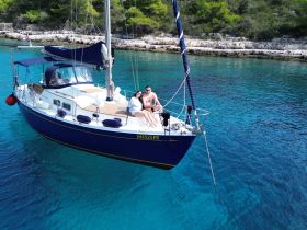 A couple enjoys a relaxing moment aboard a sailboat in crystal-clear turquoise waters, perfect for romantic getaways or sailing adventures.