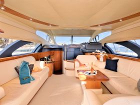 An elegant interior view of a yacht's cabin featuring plush seating and a well-equipped helm, perfect for relaxing and enjoying the journey on the water.