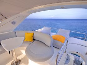 A cozy seating area inside a yacht, featuring plush cushions and a sleek table, perfect for relaxing while enjoying stunning ocean views.