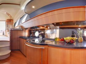 A beautifully designed boat kitchen featuring modern amenities and fresh fruits, perfect for onboard dining experiences.