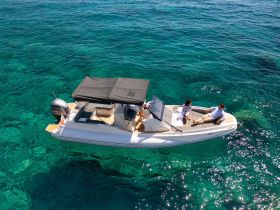 A couple relaxes on a stylish boat in crystal clear waters, perfect for enjoying a day on the sea or exploring beautiful destinations.