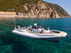 A group enjoys a sunny day on a sleek boat, surrounded by stunning coastal scenery — perfect for a relaxing outing on the water.