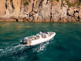 A sleek boat navigates through crystal-clear waters near rocky cliffs, showcasing an exciting day on the water.