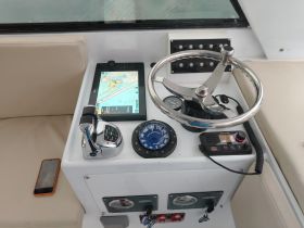 A detailed view of the helm and console area inside a boat, showcasing navigation equipment and controls — essential for steering and managing the vessel.