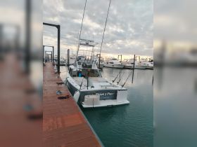A fishing boat named 'Pique y Pique' docked at a marina, showcasing its sleek design and fishing gear, perfect for a day on the water.