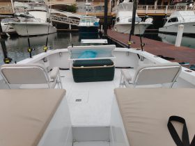 Interior view of a fishing boat showcasing comfortable seating and storage, ideal for a day out on the water.