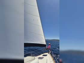 A sailor enjoys the thrill of sailing on a beautiful day, showcasing the excitement of on-water activities and the joy of being out at sea.