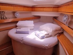 A cozy cabin interior featuring a round bed with neatly arranged pillows and towels, perfect for relaxation on a boat.