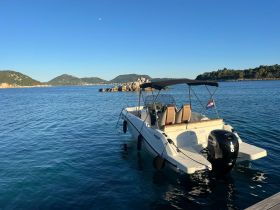 A sleek speedboat anchored in calm turquoise waters, surrounded by scenic hills — perfect for a day of exploration on the water.