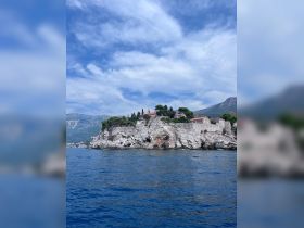 A stunning view of a coastal landmark with lush greenery and historic buildings perched on rocky cliffs, showcasing the beauty of the landscape from the water.