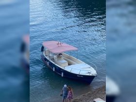 A couple walks along the beach near a boat, enjoying a serene moment by the water — perfect for romantic getaways or beach adventures.