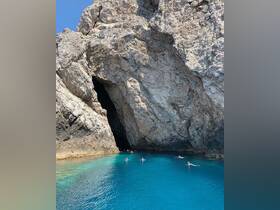Swimmers enjoy the crystal-clear waters near a stunning cave, creating a picturesque scene perfect for adventure seekers and nature lovers.