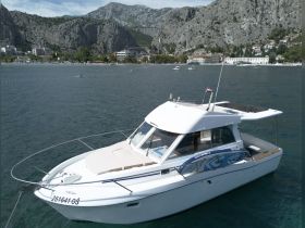 A clear view of a sleek boat docked in calm waters, showcasing its design against a stunning mountainous backdrop — perfect for exploring coastal destinations.
