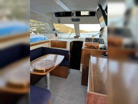 Interior view of a boat's helm and seating area, showcasing a cozy cabin design perfect for relaxing while cruising.