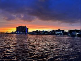 A stunning sunset over a vibrant harbor, showcasing the beautiful skyline and reflections on the water — perfect for evening boat cruises.
