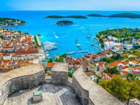 A stunning aerial view of a picturesque harbor surrounded by lush islands and charming coastal architecture, showcasing the beauty of Hvar, Croatia.