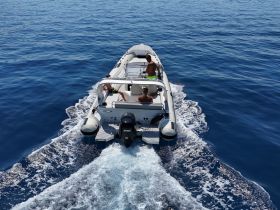 A speedboat glides through the deep blue ocean with passengers enjoying the ride, showcasing the thrill of boating adventures.